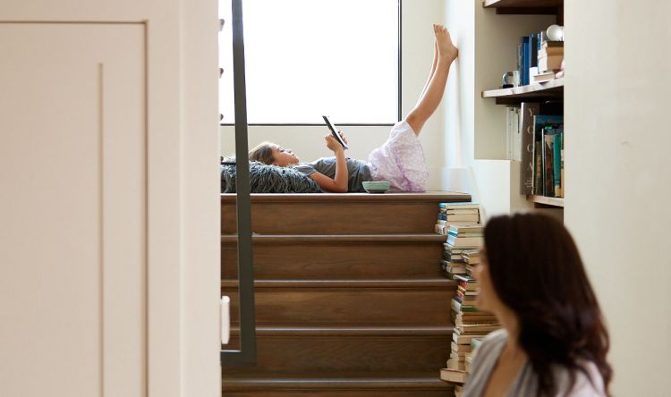Mädchen liegt zu Hause auf einem Treppenabsatz und tippt auf dem Smartphone