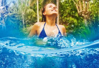 Bad Buchholz: Junge Frau badend im blauen Wasser vor üppiger Vegetation